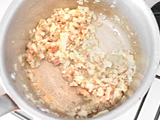 ベーコンを加えて軽く炒め、米を加え、ヌカ臭さがなくなるまで炒める。