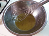 ボウルにレモンを絞り、オリーブオイル、マスタード、砂糖、塩を加え、泡立て器で混ぜる。